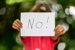 Blurred girl holding a piece of paper with the word No in front of her.
