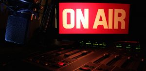 On Air sign glowing, reflecting light on a radio studio broadcast panel.